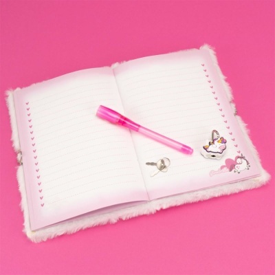 Caderno rosa peludo aberto com caneta e acessórios sobre fundo rosa