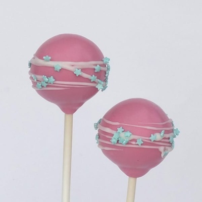 Dois cake pops cor-de-rosa com decoração de glacê branco e estrelas azuis