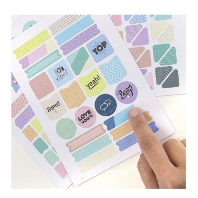 Folhas com autocolantes coloridos e uma mão a tocar um deles