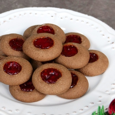 Bolachas castanhas redondas com centro de geleia vermelha em prato branco