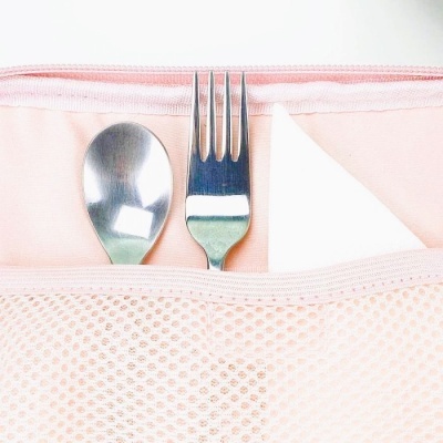 Talheres metálicos numa bolsa rosa clara de tecido com malha