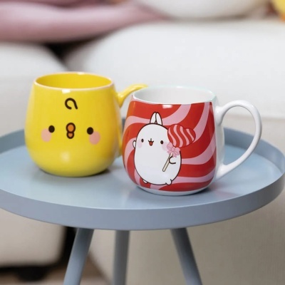 Duas canecas coloridas com desenhos de personagens em mesa azul-claro