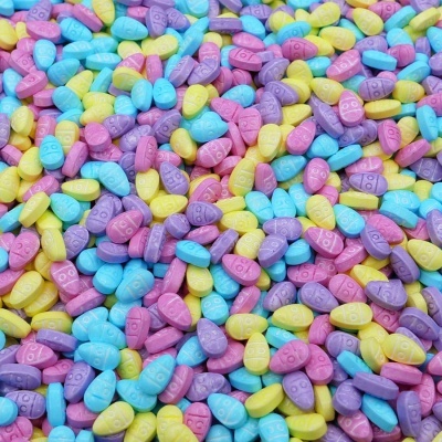 Comprimidos coloridos com gravação DB em relevo em tons azul, roxo, rosa e amarelo