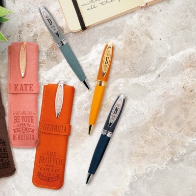 Cinco canetas com suportes de couro coloridos e gravados numa superfície de pedra clara