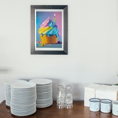 Foto de cupcake colorido em moldura preta na parede branca