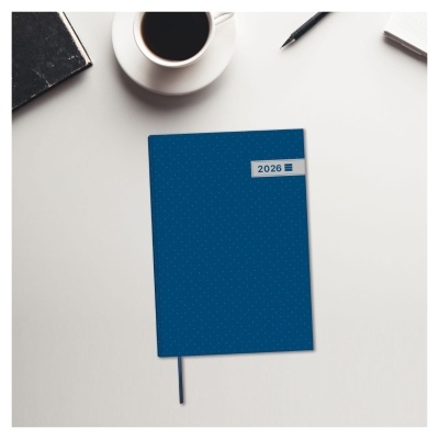 Caderno azul com etiqueta 2026 numa mesa com café, caneta e livro