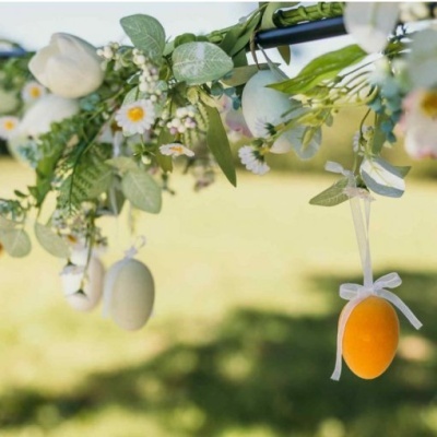 Arranjo decorativo com flores artificiais e ovos pendurados