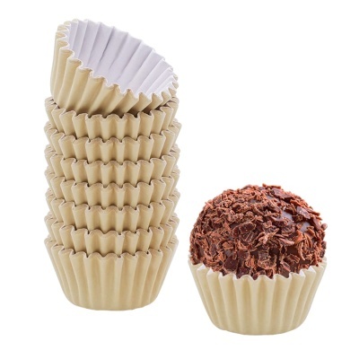 Forminhas de papel bege para doces empilhadas com brigadeiro ao lado.