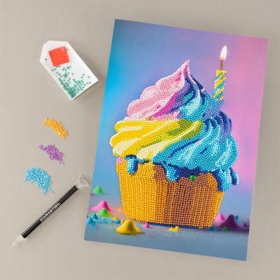 Quadro tipo pixel art de cupcake colorido com contas e vela acesa, com ferramentas e contas coloridas ao lado.