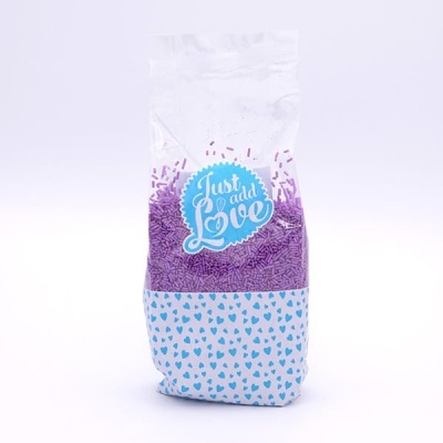 Saco transparente com granulados roxos e etiqueta azul 'Just add Love'