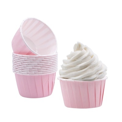 Forminhas cor-de-rosa para cupcakes, uma com creme branco.