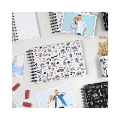 Vários cadernos espiralados com capas decoradas e fotos sobre uma mesa branca