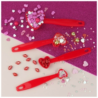 Conjunto de colheres medidoras vermelhas em forma de coração com confeitos coloridos