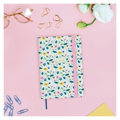 Caderno Flores 2026 com acessórios de escritório em fundo rosa