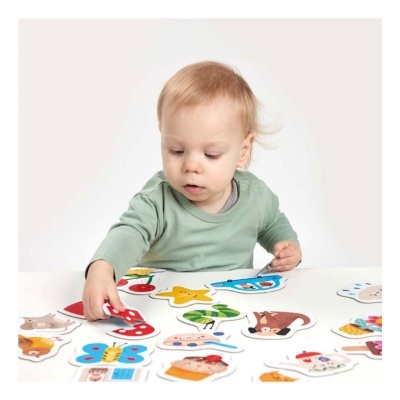 Criança a brincar com peças de puzzle coloridas numa mesa branca