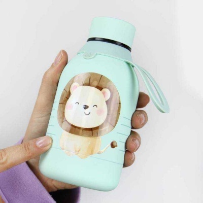 Garrafa azul claro com desenho de leão e tampa roxa segurada por mãos