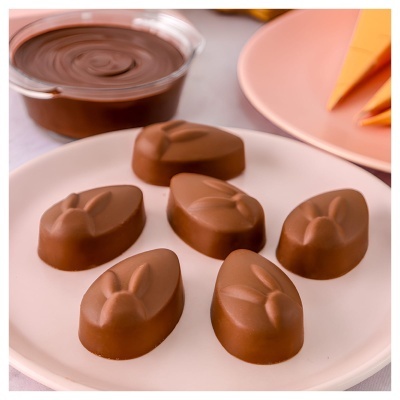 Bombons de chocolate em forma oval com relevo de coelho sobre prato branco