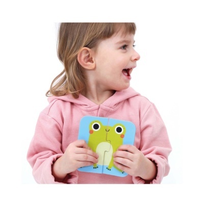 Criança com casaco rosa segurando puzzle de sapo verde