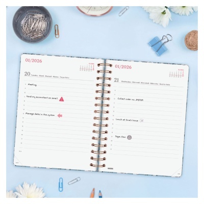 Agenda aberta em superfície azul com clips e flores brancas