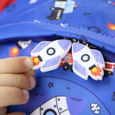 Mochila azul com padrão espacial e fechos em forma de foguetões coloridos
