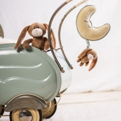 Carrinho verde com coelhinhos de pelúcia e lua pendurada