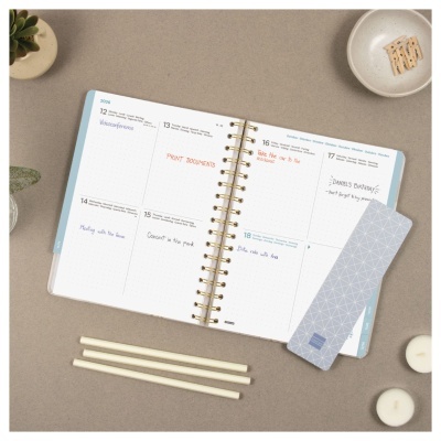 Agenda semanal aberta com marcador cinza e decoração em fundo bege
