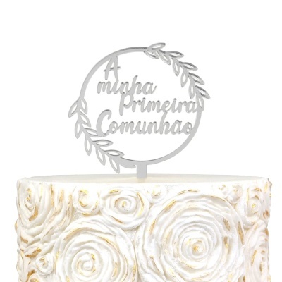 Topo de bolo prateado com texto A minha Primeira Comunhão e bolo branco decorado com rosas em relevo