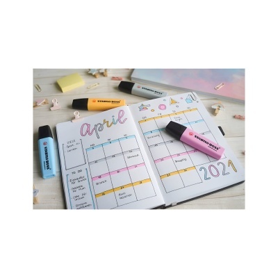 Calendário mensal de abril 2021 com canetas Stabilo BOSS coloridas e artigos de papelaria sobre uma mesa clara