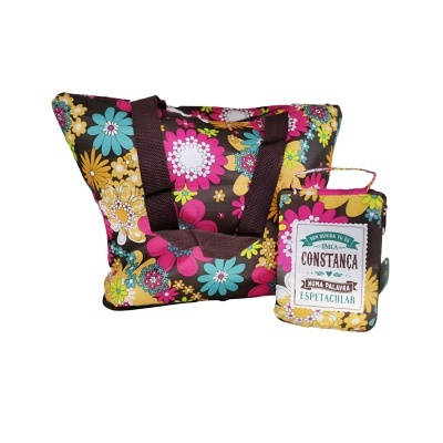 Saco e estojo florais com alças castanhas e etiqueta com texto em português