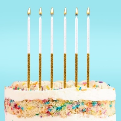 Bolo de aniversário com velas finas brancas com glitter dourado a arder