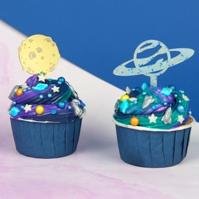 Dois cupcakes decorados com glacê colorido e toppers espaciais