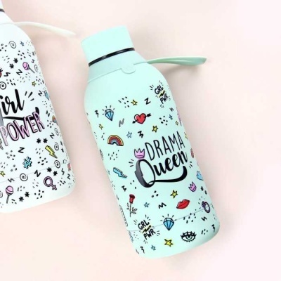 Garrafa de água azul clara com texto DRAMA Queen e desenhos coloridos ao lado de garrafa branca com texto GIRL POWER