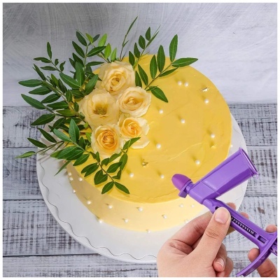 Bolo amarelo decorado com flores amarelas e folhas verdes, com aplicador roxo na mão.