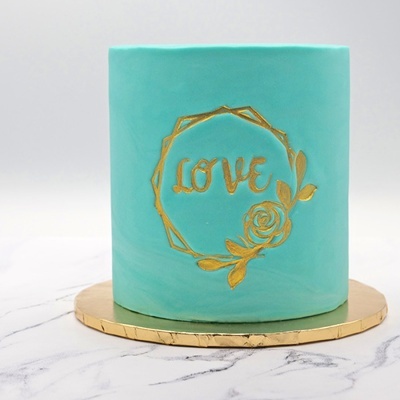 bolo azul turquesa decorado com a palavra LOVE em dourado