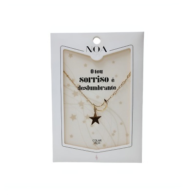 Colar dourado com pendente estrela e lua na embalagem branca com texto em português.