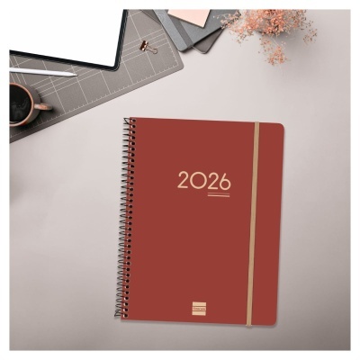 Agenda castanha 2026 com elástico bege sobre mesa clara