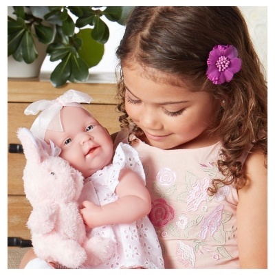 Menina a segurar boneca bebé e peluche coelho rosa