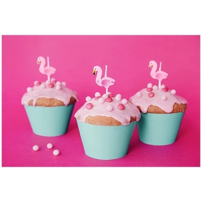 Cupcakes com cobertura rosa, confeitos e velas flamingo em forminhas azuis