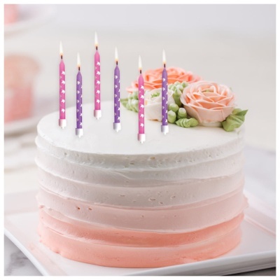 Bolo decorado com flores de creme e velas acesas coloridas