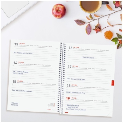 Agenda semanal branca com mãos encaderno espiral, maçã, caneca e folhas de outono sobre uma mesa branca