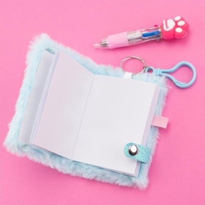 Caderno de pelúcia azul com caneta decorada em fundo rosa