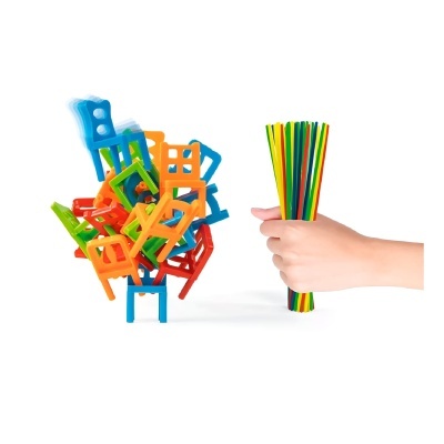 Mini cadeiras coloridas empilhadas e mão segurando varetas coloridas