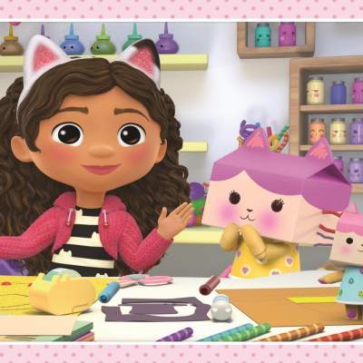 Menina animada com orelhas de gato e figuras de papel de gatos numa mesa de artesanato colorida