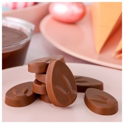 Ovos de chocolate ao leite com relevo de orelhas de coelho sobre superfície branca