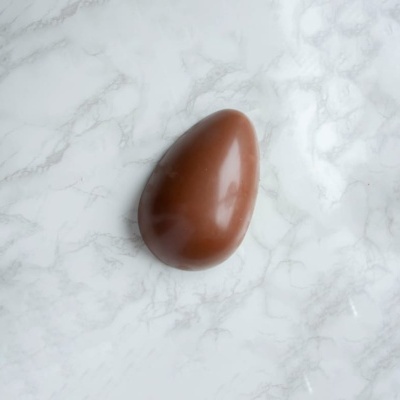 Ovo de chocolate castanho sobre mármore branco