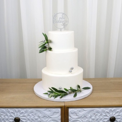 Bolo branco de três andares com decoração verde e prateada e topper de acrílico com texto