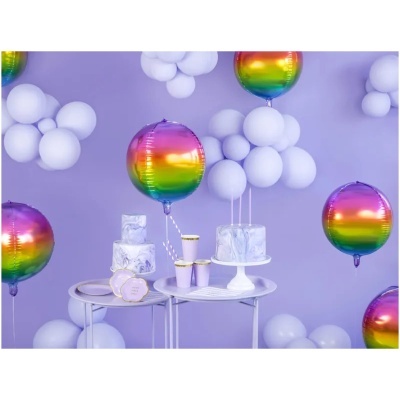 Mesa com bolo marmoreado, copos lilás dourados, balões brancos e metalizados multicoloridos em fundo roxo.