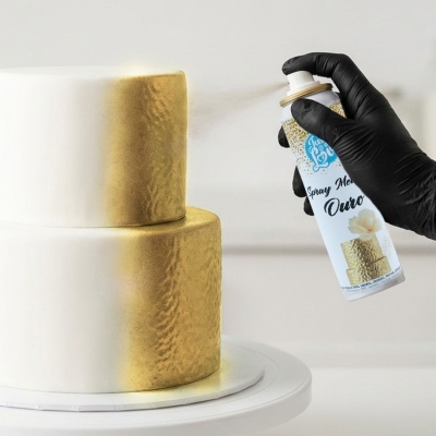 Pulverização de spray metálico dourado em bolo branco de dois andares.