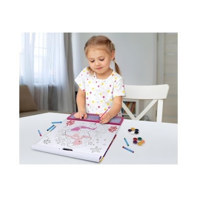 Menina a pintar num livro para colorir com giz de cera numa mesa branca