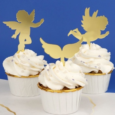 Cupcakes com cobertura branca, pérolas e enfeites dourados de anjos e asas